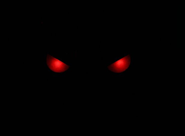 A pair of red eyes stare towards the viewer, wreathed in darkness.